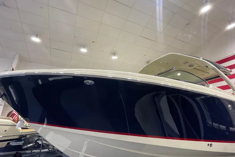 Slide: The Image of 2026 Chris-Craft Launch 31 GT boat in showroom, sleek design, navy hull. - 80