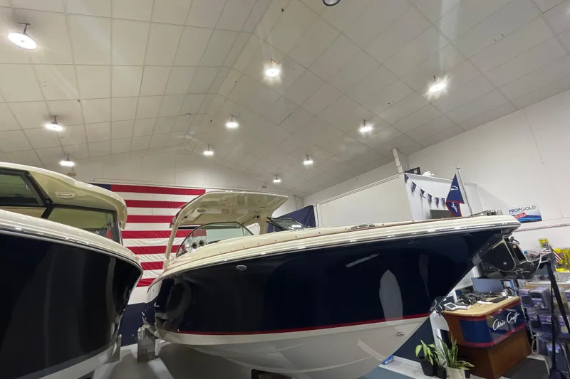 Slide: The Image of 2026 Chris-Craft Launch 31 GT boat displayed indoors with American flag backdrop. - 82