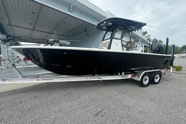 Slide: The Image of 2025 Sportsman Masters 267OE Bay Boat on trailer, sleek black design, parked outdoors. - 18