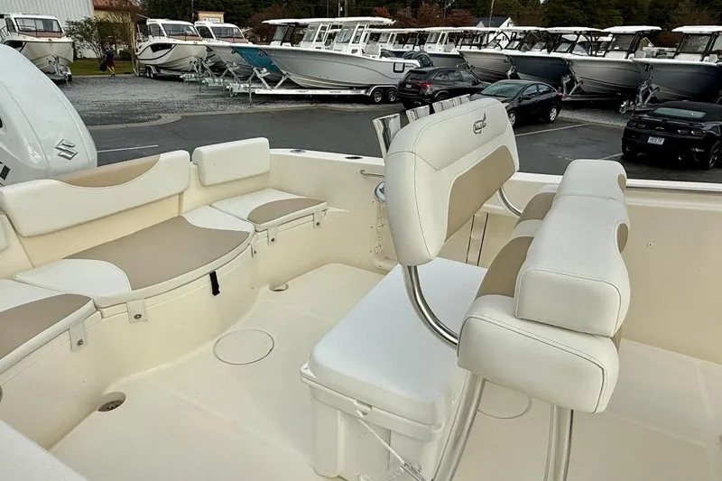 Slide: The Image of 2026 Bulls Bay 230 Center Console boat interior with seating and helm, parked in a marina. - 13