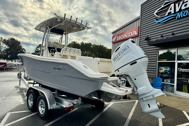 Slide: The Image of 2026 Bulls Bay 230 Center Console boat with Suzuki engine on trailer, parked outside dealership. - 5