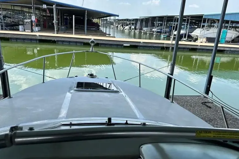 Slide: The Image of 2004 Sea Ray 260 Sundancer docked at marina with green water and covered slips. - 21