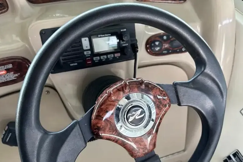 Slide: The Image of Steering wheel of a 2004 Sea Ray 260 Sundancer boat, featuring wood accents. - 24