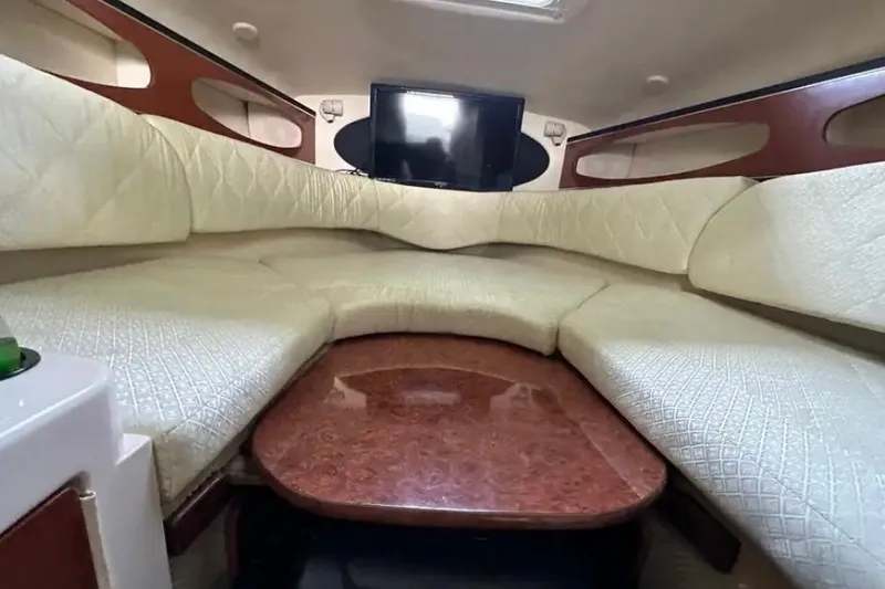 Slide: The Image of Interior of 2004 Sea Ray 260 Sundancer with cushioned seating and a mounted TV. - 32