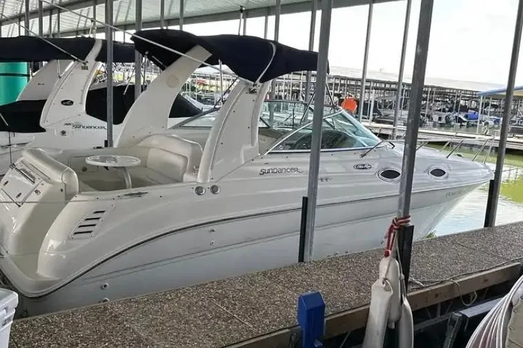 Slide: The Image of 2004 Sea Ray 260 Sundancer docked in a marina, featuring sleek design and covered seating. - 4