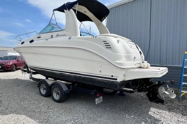 Slide: The Image of 2004 Sea Ray 260 Sundancer boat on trailer, parked outdoors near a metal building. - 49