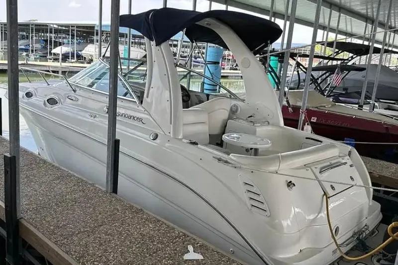 Slide: The Image of 2004 Sea Ray 260 Sundancer docked in a marina, featuring sleek white design and canopy. - 5