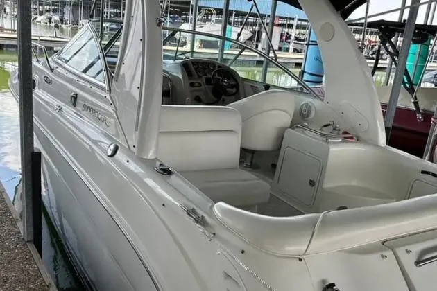 Slide: The Image of 2004 Sea Ray 260 Sundancer boat docked, showcasing sleek white design and spacious cockpit. - 7