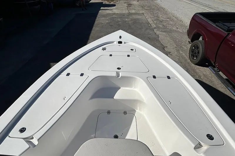 Slide: The Image of 2026 Sea Pro 210 Bay boat deck with storage compartments, parked near a red truck. - 43