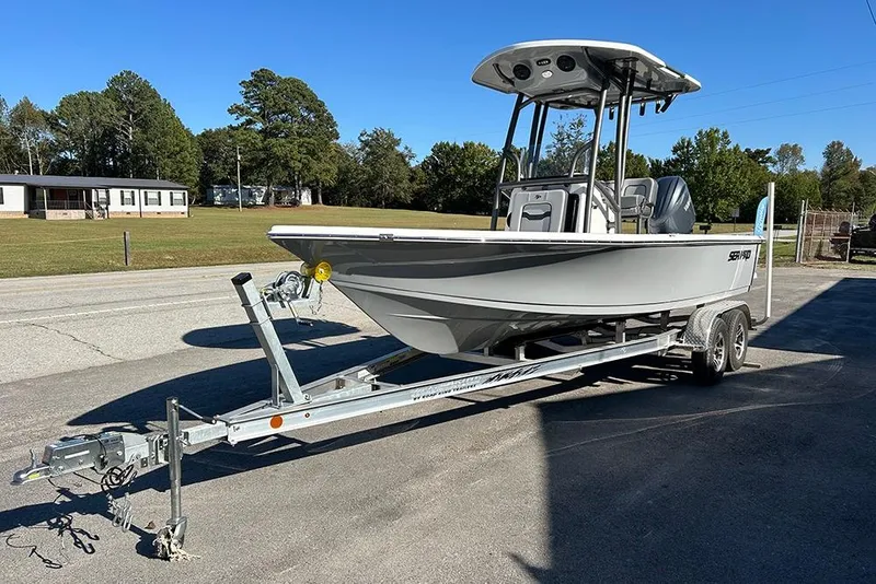 Slide: The Image of 2026 Sea Pro 210 Bay boat on trailer, parked outdoors under clear blue sky. - 9