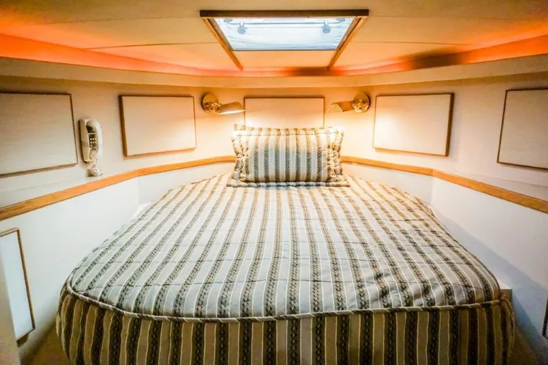 Slide: The Image of Cozy bedroom in 1987 Bertram 54 Convertible yacht with striped bedding and warm lighting. - 19