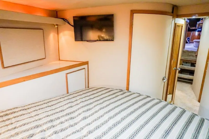 Slide: The Image of Interior of 1987 Bertram 54 Convertible yacht bedroom with TV and striped bedding. - 21