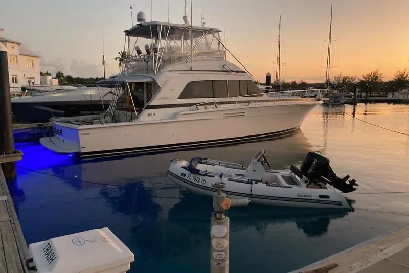 Slide: The Image of 1987 Bertram 54 Convertible yacht docked at sunset with a small boat nearby. - 27
