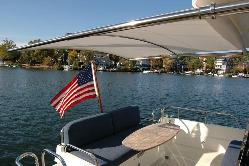 Slide: The Image of 2019 Sabre 38 Salon Express yacht with American flag, scenic waterfront view. - 49