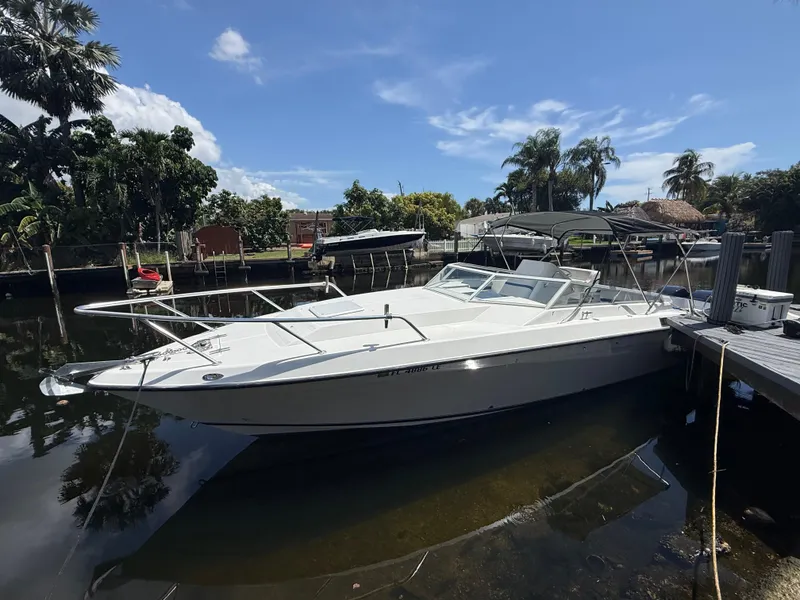 Slide: The Image of 2000 Contender 35 Side Console boat docked by a scenic waterfront with palm trees. - 10