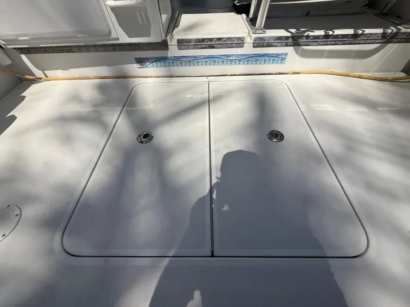 Slide: The Image of 2000 Contender 35 Side Console boat deck with storage hatches and measuring tape. - 15