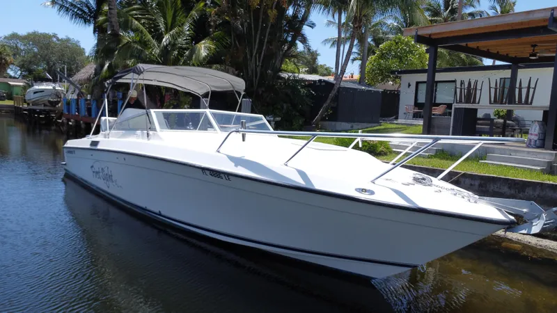 Slide: The Image of 2000 Contender 35 Side Console boat docked by a waterfront home with palm trees. - 2