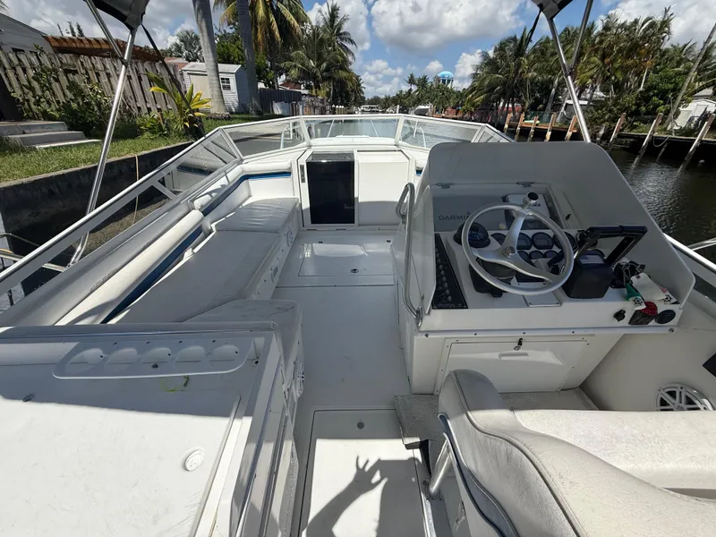 Slide: The Image of 2000 Contender 35 Side Console boat interior with steering wheel and seating, docked by a canal. - 25