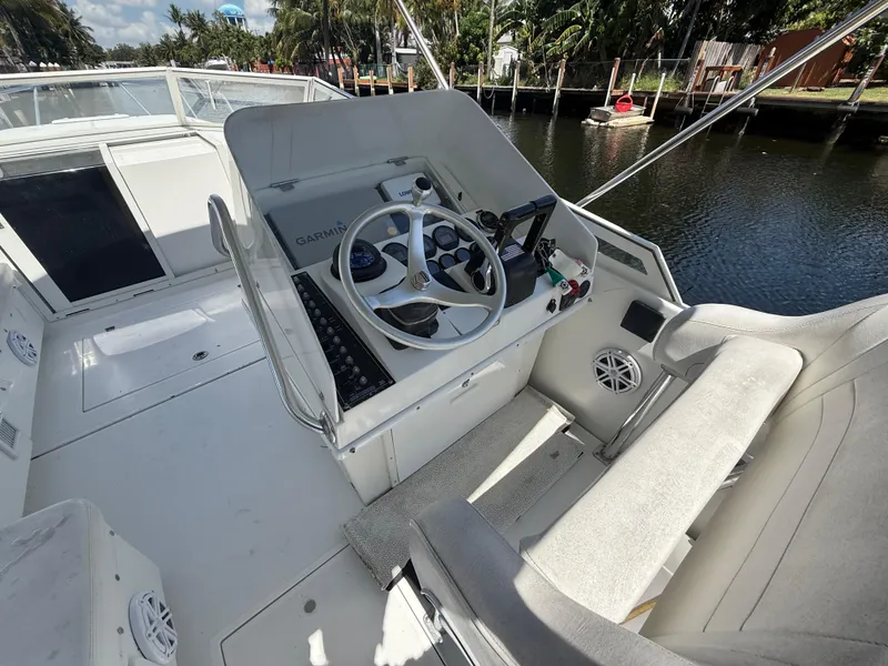 Slide: The Image of 2000 Contender 35 Side Console boat interior with steering wheel and seating, docked by a canal. - 26