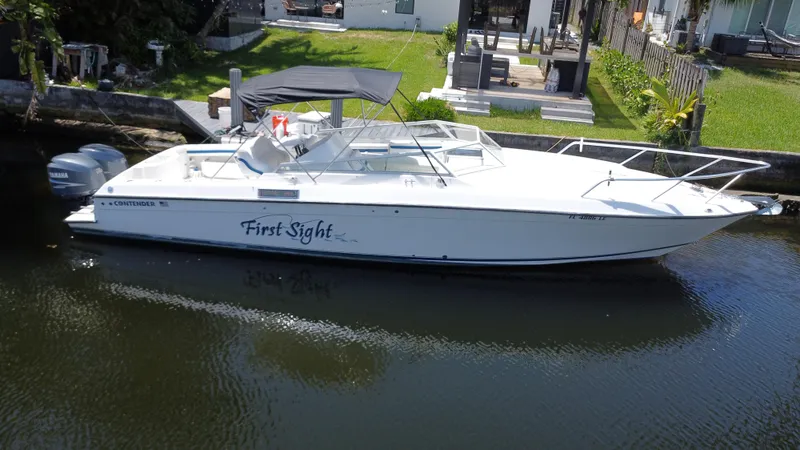 Slide: The Image of 2000 Contender 35 Side Console boat docked by a waterfront home. - 3