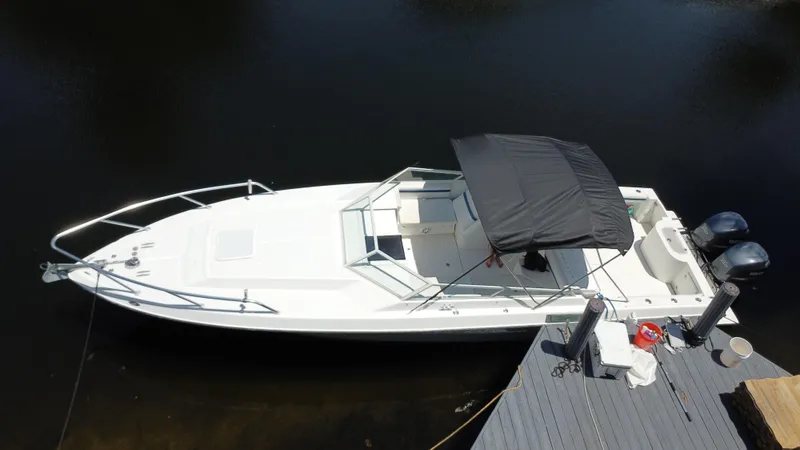 Slide: The Image of 2000 Contender 35 Side Console boat docked, featuring dual outboard motors and a black canopy. - 8