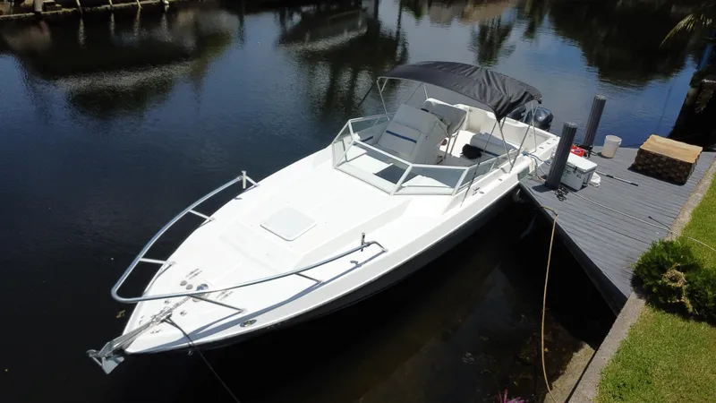 Slide: The Image of 2000 Contender 35 Side Console boat docked on calm water, featuring sleek design and canopy. - 9