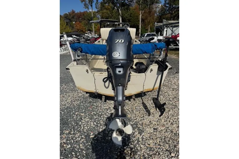 Slide: The Image of 1973 Boston Whaler 17 Montauk with outboard motor, parked on gravel lot. - 2