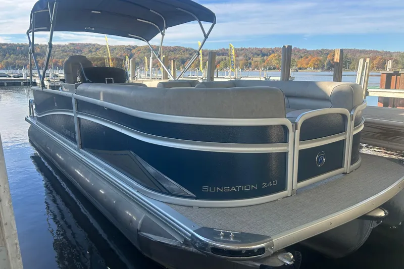 Slide: The Image of 2019 Premier 240 SunSation pontoon boat with Mercury outboard, parked near green buildings. - 6