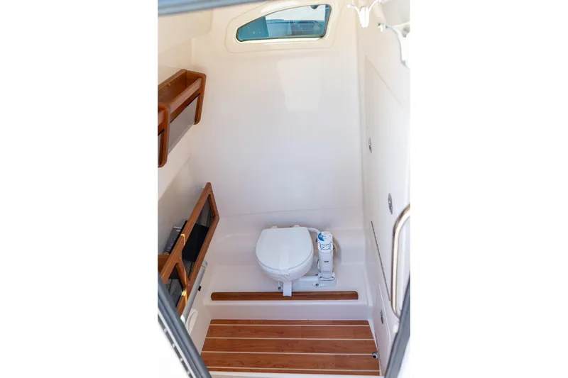 Slide: The Image of 2026 Grady-White 281 Coastal Explorer boat interior with compact marine toilet and wooden accents. - 35