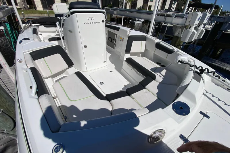 Slide: The Image of 2021 Tahoe 2150 CC boat interior with seating and console, docked by the water. - 26