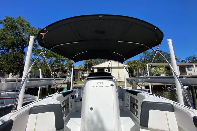 Slide: The Image of 2021 Tahoe 2150 CC boat with canopy, docked near waterfront homes. - 31