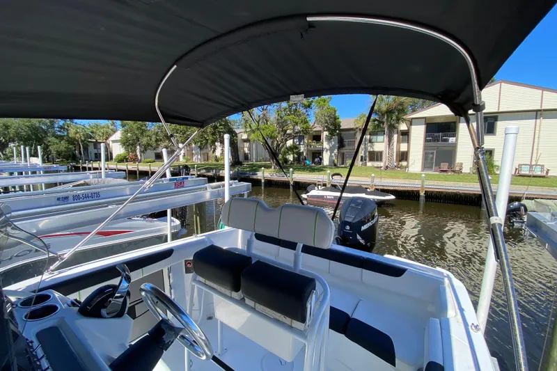 Slide: The Image of 2021 Tahoe 2150 CC boat with canopy, docked near waterfront homes. - 32