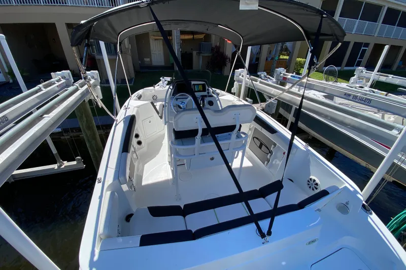 Slide: The Image of 2021 Tahoe 2150 CC boat with canopy, docked near waterfront homes. - 33