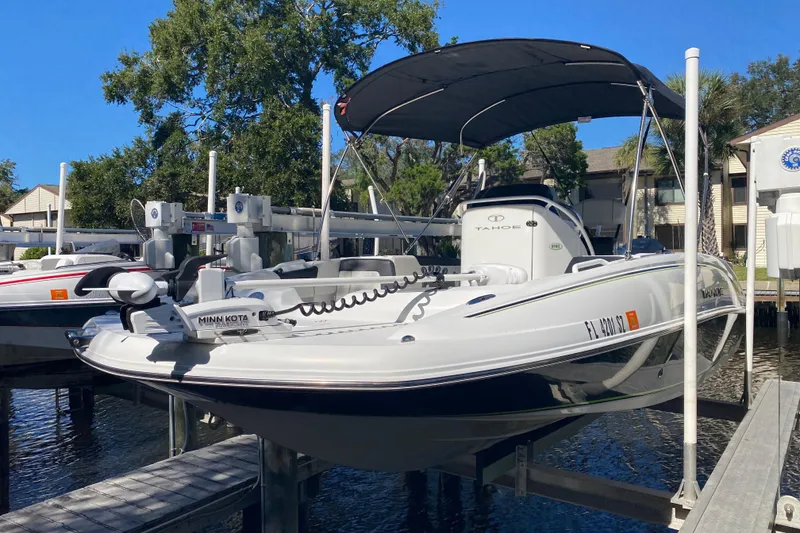 Slide: The Image of 2021 Tahoe 2150 CC boat docked with canopy, featuring Minn Kota trolling motor. - 34