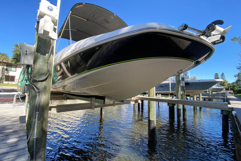 Slide: The Image of 2021 Tahoe 2150 CC boat on lift, docked by waterfront under clear blue sky. - 36