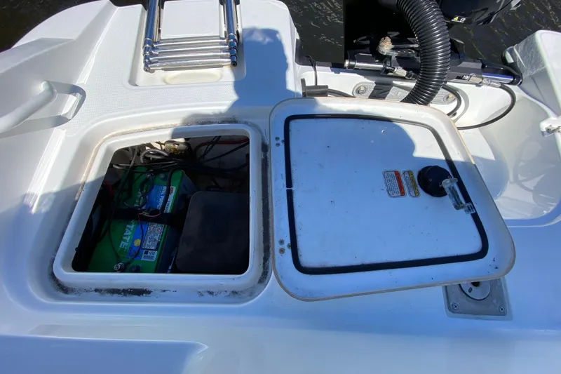 Slide: The Image of 2021 Tahoe 2150 CC boat battery compartment with open hatch and visible wiring. - 42