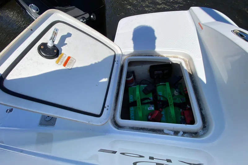 Slide: The Image of Open battery compartment on 2021 Tahoe 2150 CC boat, showing green batteries and charger. - 46