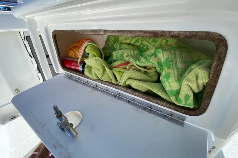 Slide: The Image of Storage compartment on a 2021 Tahoe 2150 CC boat with towels and a can. - 51
