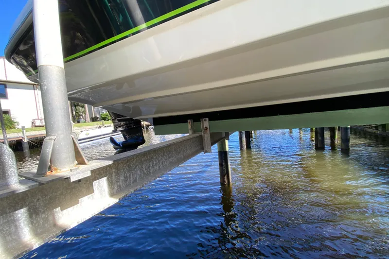 Slide: The Image of 2021 Tahoe 2150 CC boat on lift above water, showcasing hull and motor. - 65