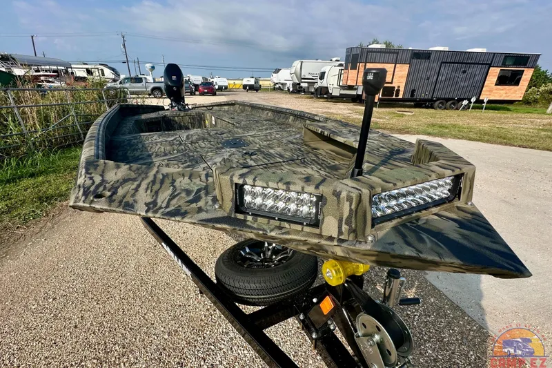 Slide: The Image of 2026 SeaArk 1752 Slayer X Pro boat with camouflage design and LED lights on a trailer. - 1