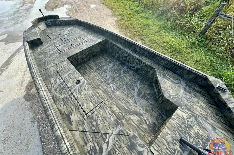 Slide: The Image of 2026 SeaArk 1752 Slayer X Pro boat with camouflage design, parked on a grassy area. - 11