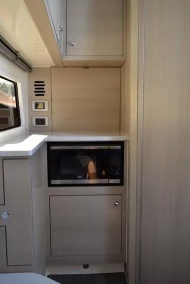 Slide: The Image of 2023 Scout 377 LXF interior kitchen area with microwave and storage cabinets. - 17
