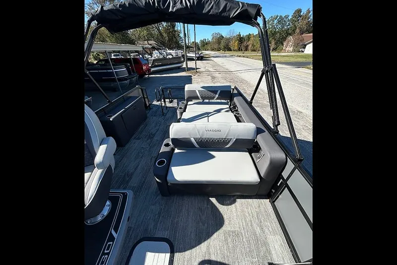 Slide: The Image of 2025 Viaggio Z22D boat interior with gray seating and cup holders, parked outdoors. - 16