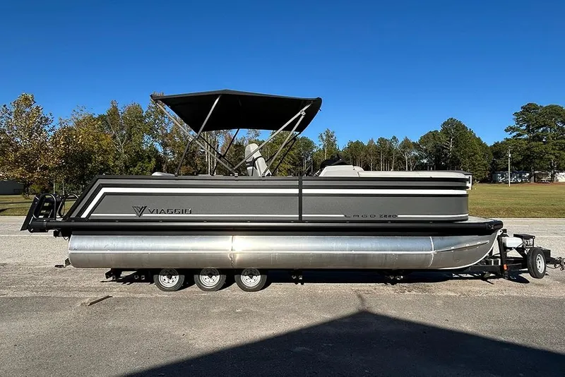 The Image of 2025 Viaggio Z22D pontoon boat on trailer, parked outdoors under clear blue sky. - 2