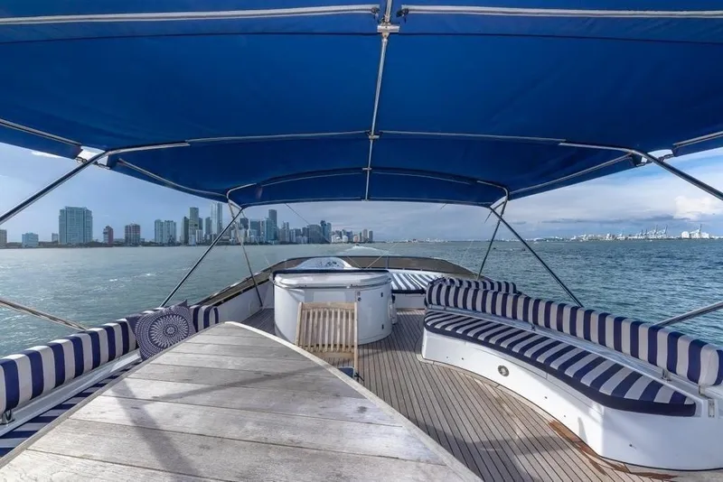 Slide: The Image of Sunseeker 82 Yacht 2003 with striped seating, city skyline view, and blue canopy. - 6