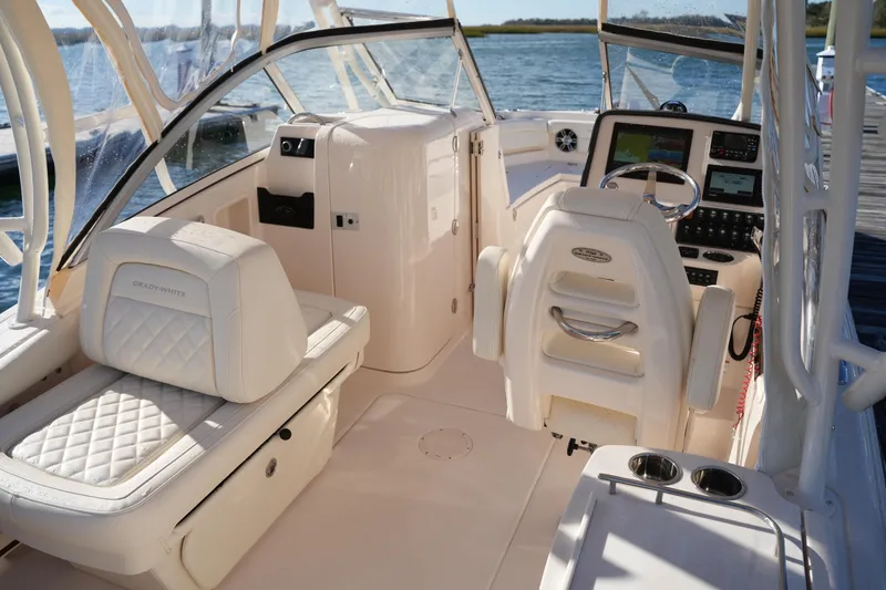 Slide: The Image of 2022 Grady-White Freedom 235 boat interior with helm and seating, docked by the water. - 21