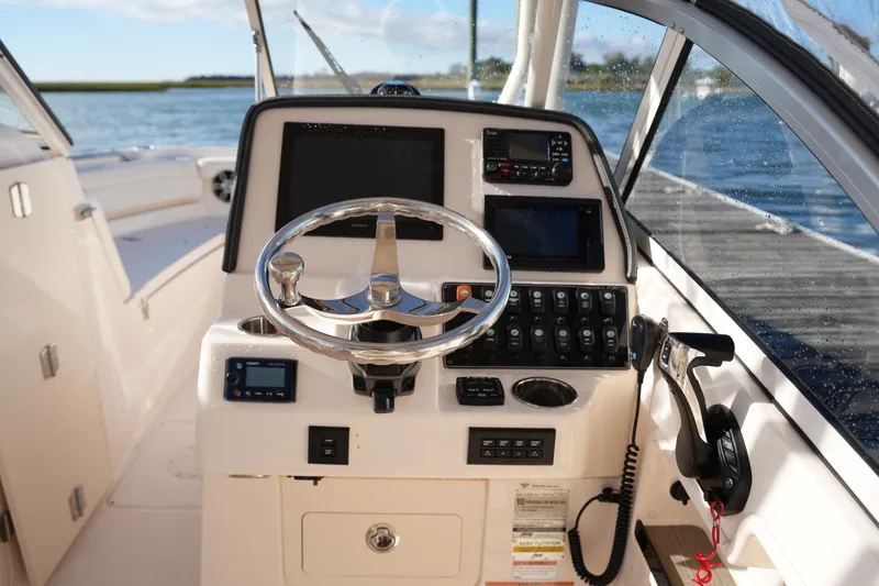 Slide: The Image of 2022 Grady-White Freedom 235 boat dashboard with steering wheel and control panel. - 25