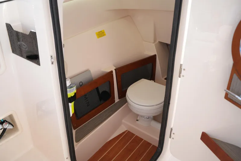 Slide: The Image of 2022 Grady-White Freedom 235 boat interior with compact marine toilet and storage. - 35