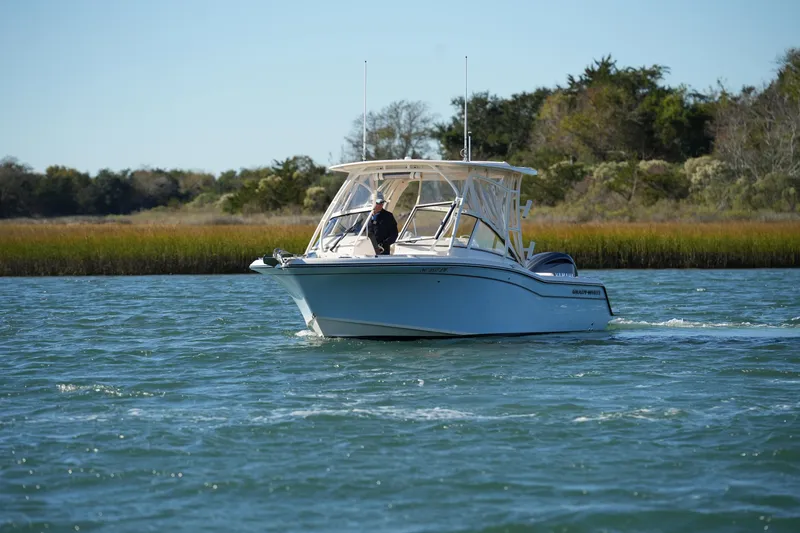 Slide: The Image of 2022 Grady-White Freedom 235 boat cruising on a scenic waterway. - 6