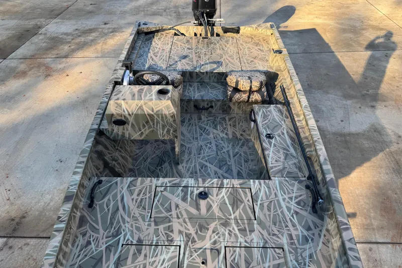 Slide: The Image of 2026 Lund 1760 Predator SC boat with camouflage design, parked on concrete surface. - 3